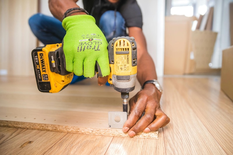 Un hombre utilizando un taladro eléctrico para atornillar una pieza de madera.