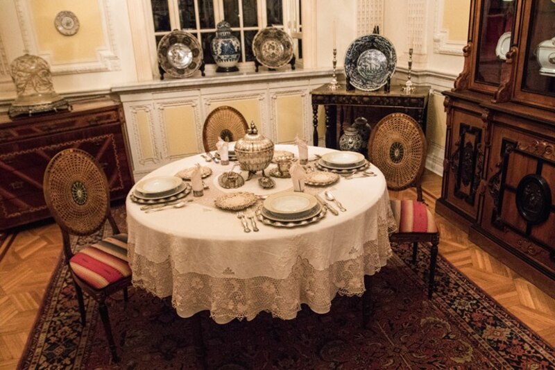 Comedor antiguo con mesa redonda y sillas de mimbre.