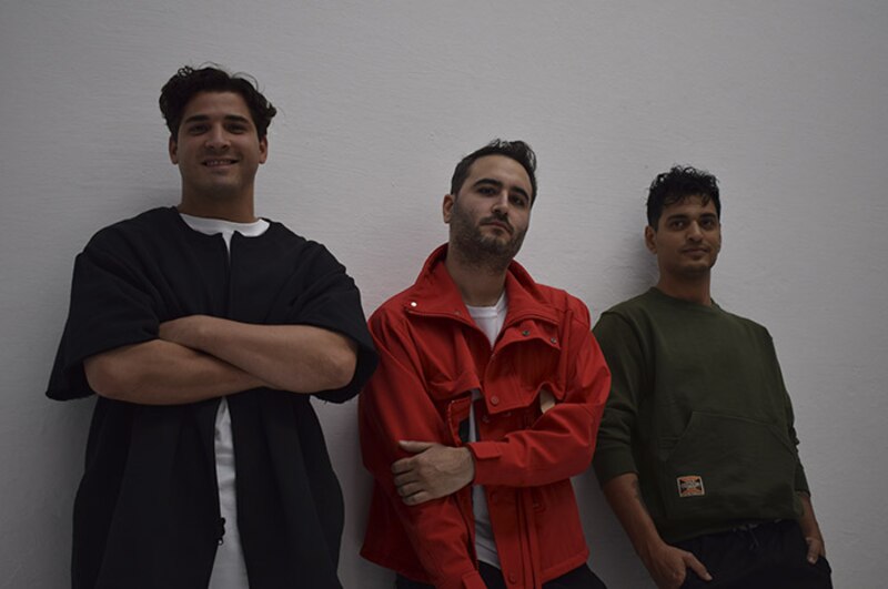 Tres jóvenes sonríen a la cámara.