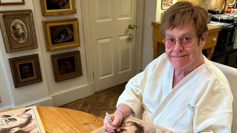 Elton John firmando un autógrafo