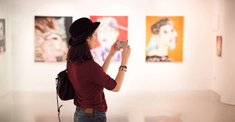 Mujer tomando una foto de una pintura en un museo