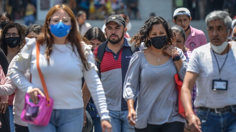 Multitud de personas con mascarillas caminando por una calle de la ciudad