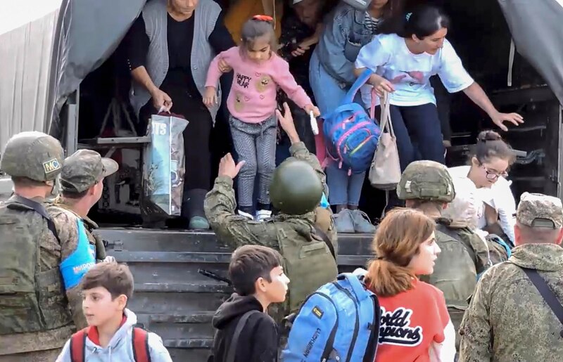 Soldados ayudan a niños y mujeres a subir a un camión
