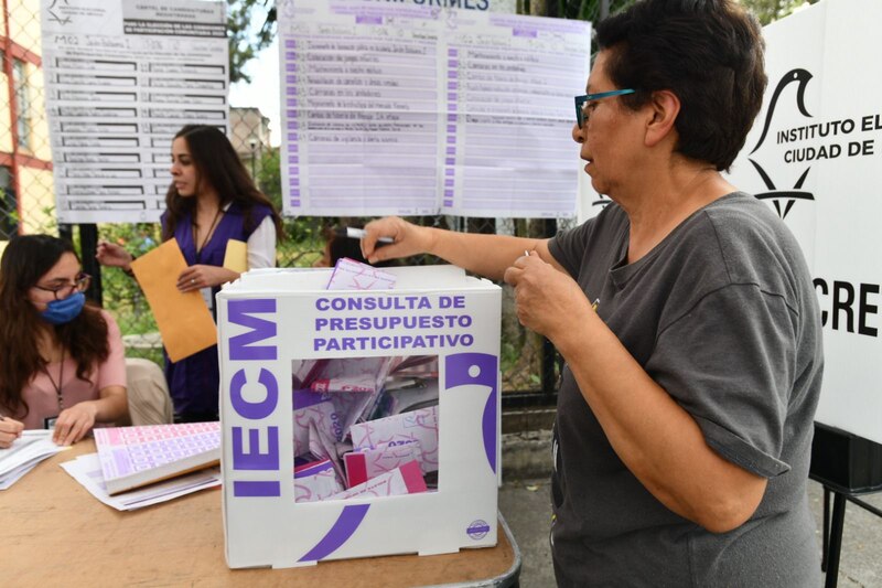 Mujer deposita su voto en una urna durante una consulta de presupuesto participativo