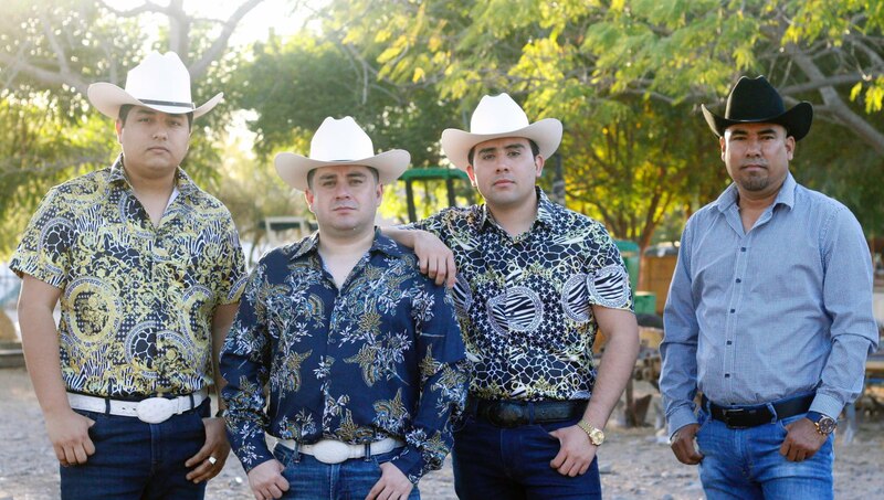 Cuatro hombres vestidos con sombreros vaqueros y camisas de manga larga posan para una foto.