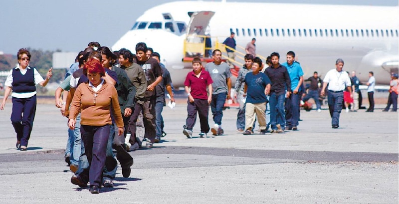 Un grupo de personas camina por una pista de aterrizaje hacia un avión.