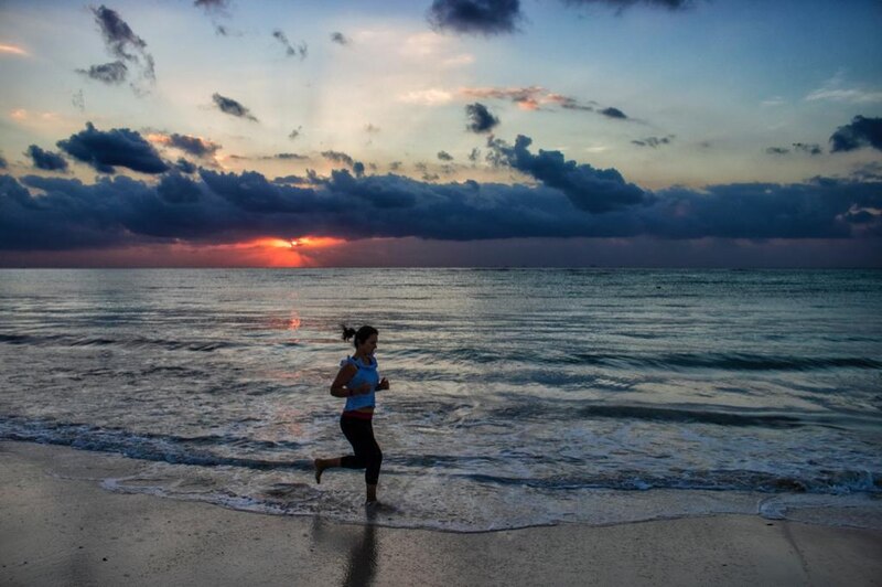 Mujer corriendo en la playa al atardecer