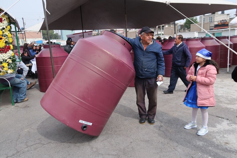 Un hombre sostiene un tanque de agua de plástico.