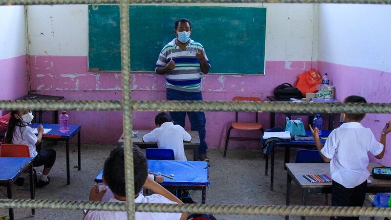 Profesor con mascarilla dando clase a niños en un aula