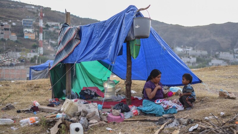 Madre e hijo migrantes descansan en un campamento improvisado