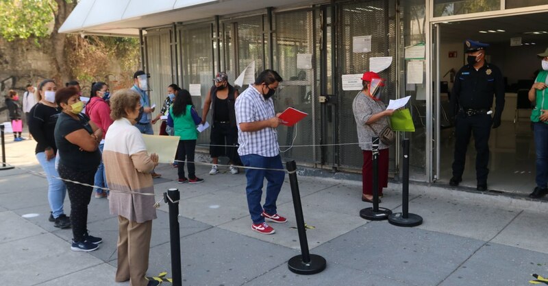 Larga fila de personas esperando para entrar a un edificio