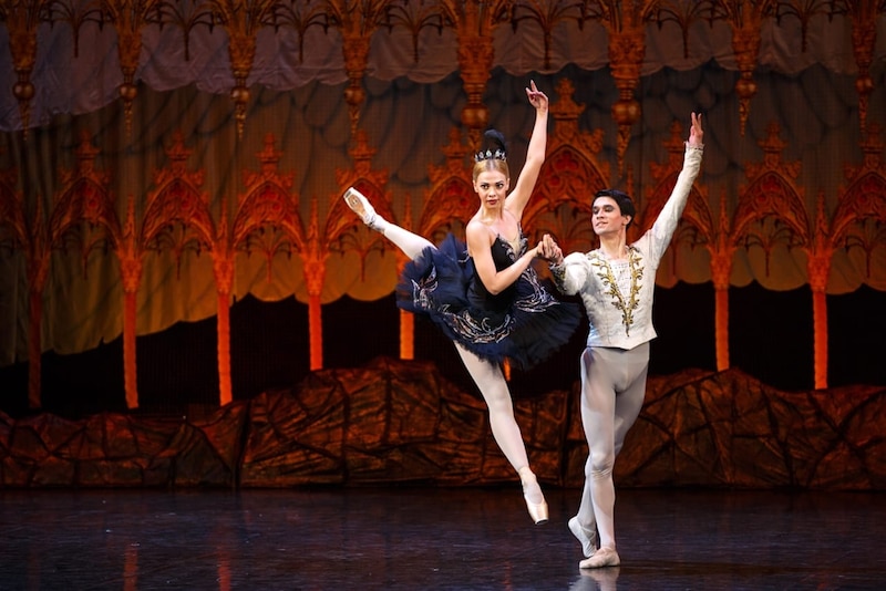 Bailarina de ballet interpretando El Lago de los Cisnes en escenario iluminado