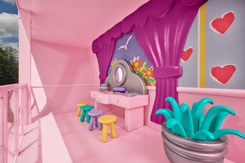 Una habitación rosa con un tocador y tres sillas