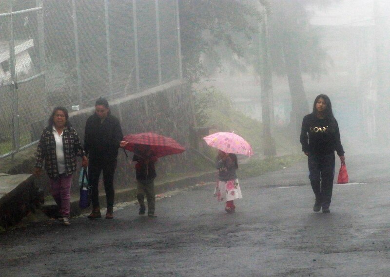 Mujeres y niños caminando bajo la lluvia