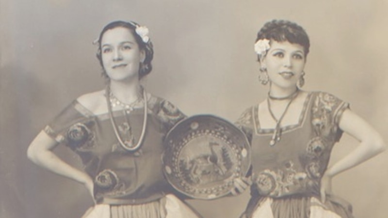 Dos mujeres jóvenes vestidas con trajes tradicionales mexicanos.