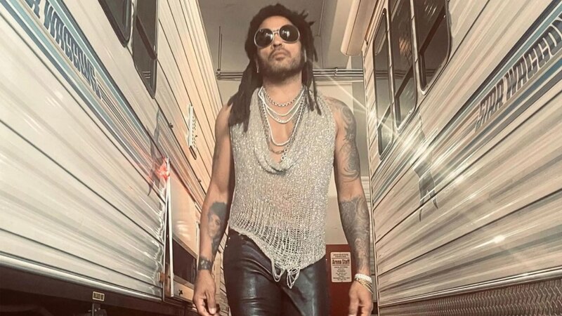 El cantante Lenny Kravitz, con un chaleco de malla transparente y pantalones de cuero negro, se encuentra en un camerino.