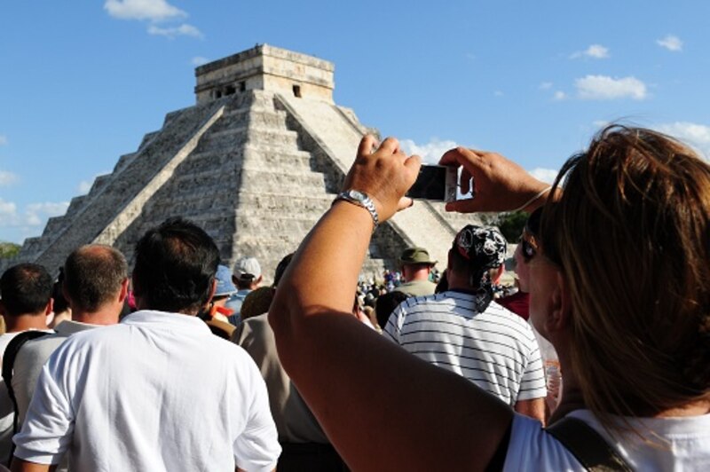 Mujer tomando una foto de la Pirámide de Chichén Itzá