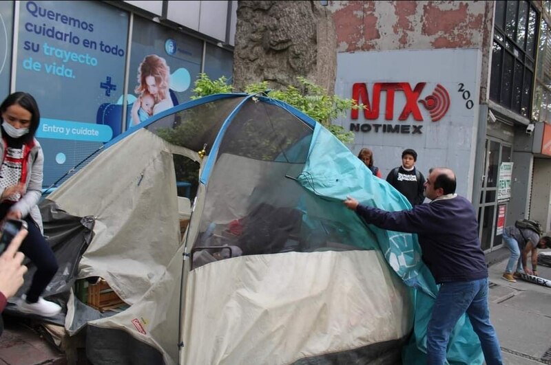 Una mujer y un hombre instalan una tienda de campaña en la calle.