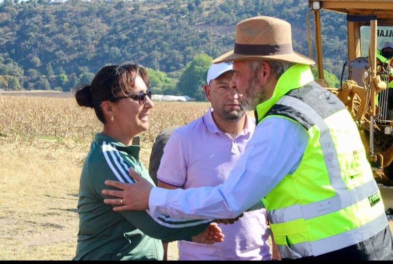 El presidente López Obrador saluda a una mujer en un campo de cultivo.