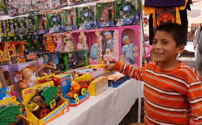Niño indígena sonriendo frente a un puesto de juguetes