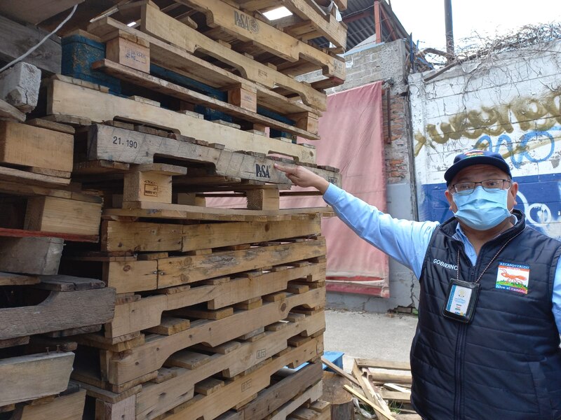 Un trabajador señala una tarima de madera.