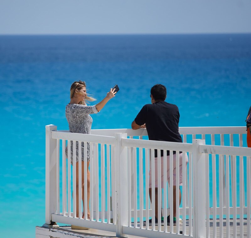 Pareja de turistas tomando una foto del mar Caribe en Cancún