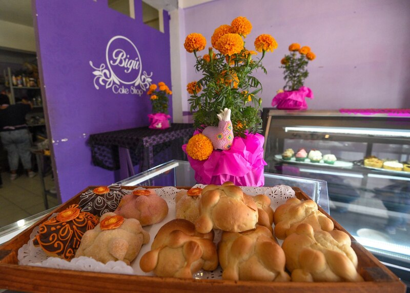 Daniela Colín de la Pastelería Bigú Cake Shop desde hace cuatro años elabora pan de muerto, buscando conservar las tradiciones y alejarse de la línea comercial que marca todo con mucha azúcar, con cada una de las piezas que hornea busca lo más cercano a nuestras costumbres, utilizando productos de la temporada, sabores como  azahar  y naranja, relleno de ate de membrillo y queso, Guayaba con queso y un especial de crema pastelera con mandarina y el imperdible de Chocolate es algo que se puede encontrar en su local ubicado en la colonia Francisco Murguía en la ciudad de Toluca, uno  de los decorados de chocolate en blanco y naranja está inspirado en el pan de Muerto de Mitla y  en cada uno de las piezas colocan  una pequeña flor de cempasúchil que es de azúcar. Empiezan a ofrecer este pan la primera semana de octubre y terminan la primera semana de noviembre, regularmente en tienda tiene pocas piezas de cada sabor ya que recomiendan a sus clientes realizar su pedido con anticipación, todo se hornea y decora al día. Invita a la población a  darle oportunidad a los pequeños  negocios y contribuir al consumo local.