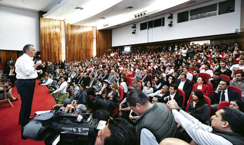El presidente da un discurso ante una multitud en un auditorio.