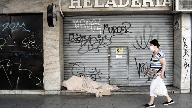 Mujer pasa junto a un indigente en la calle