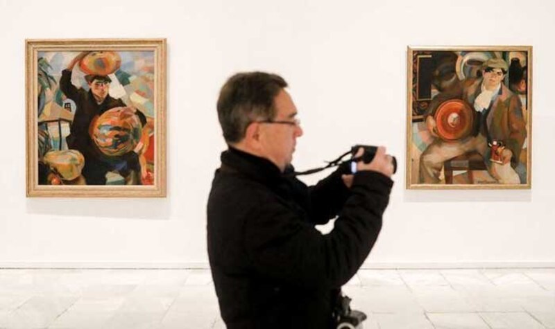 Un hombre toma una foto de un cuadro en un museo.