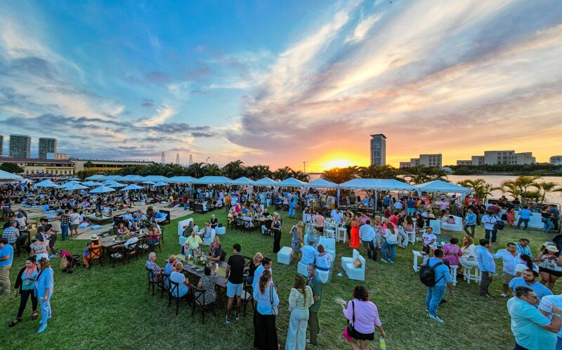 Una multitud de personas se reúne en un parque para disfrutar de una noche de comida, bebida y música.