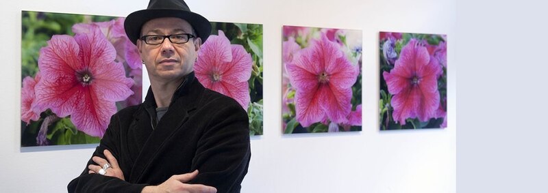 Artista contemporáneo frente a sus obras de arte floral.