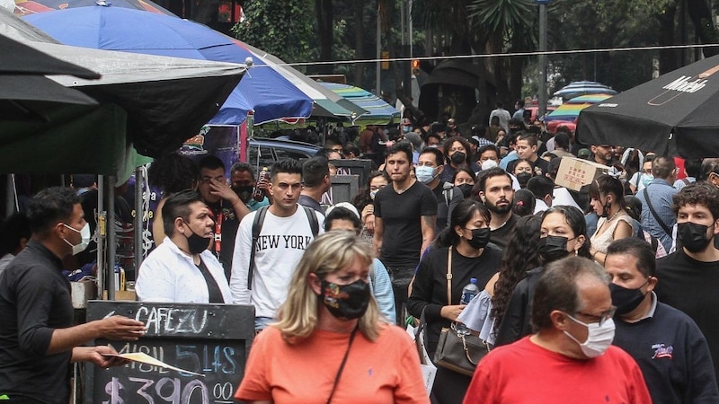 Multitud de personas con mascarillas caminando por una calle en el centro de la ciudad