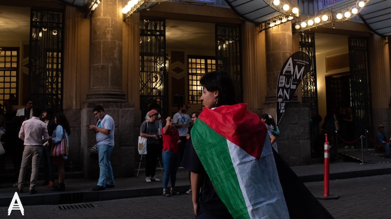 Mujer con una bandera Palestina en la espalda