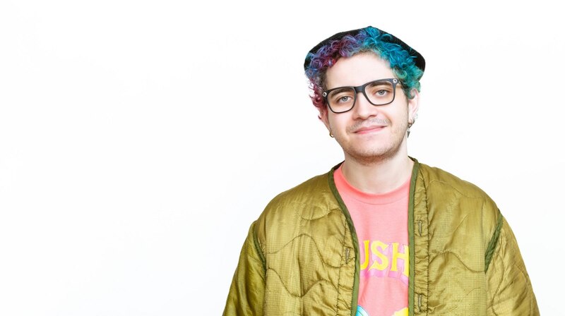 Joven con pelo azul y gafas sonríe