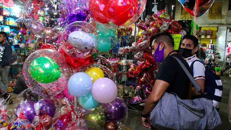 Un hombre camina junto a un puesto de globos.