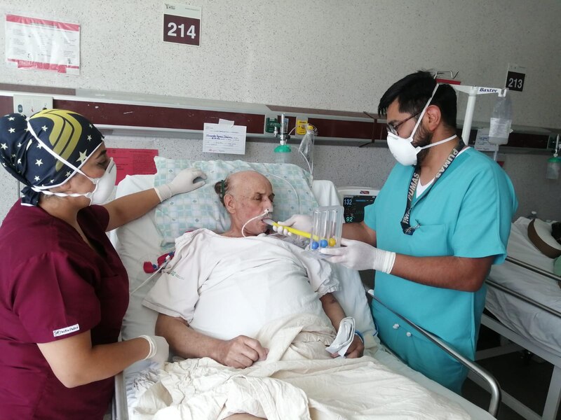 Paciente anciano en cama de hospital con personal médico