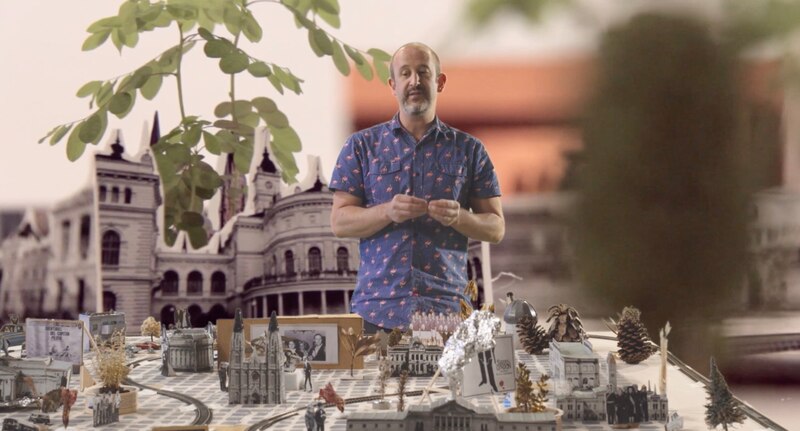 Un hombre en una mesa con una maqueta de una ciudad