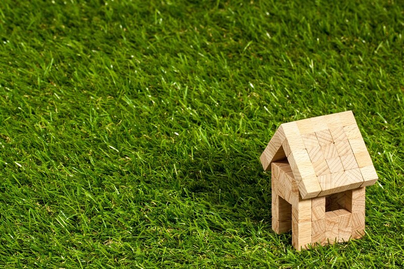 Casa de madera en miniatura sobre césped verde