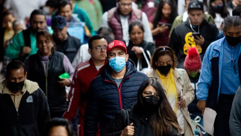 Multitud de personas con mascarillas caminando por una calle de la ciudad