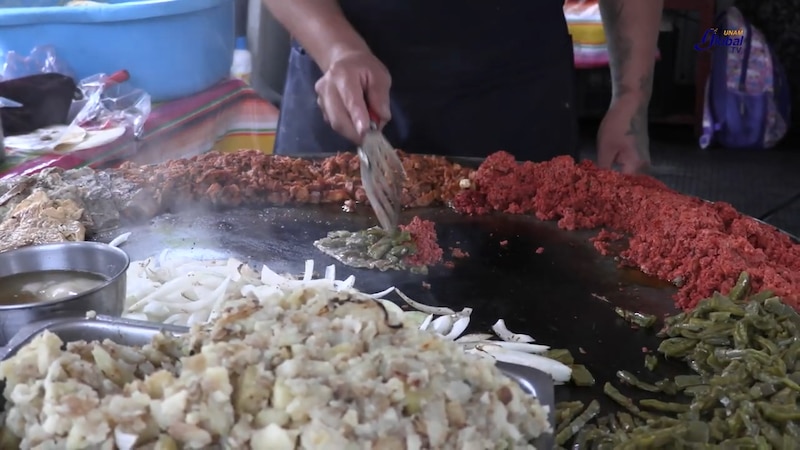 Un puesto de comida en la calle vende una variedad de carnes y verduras a la parrilla.