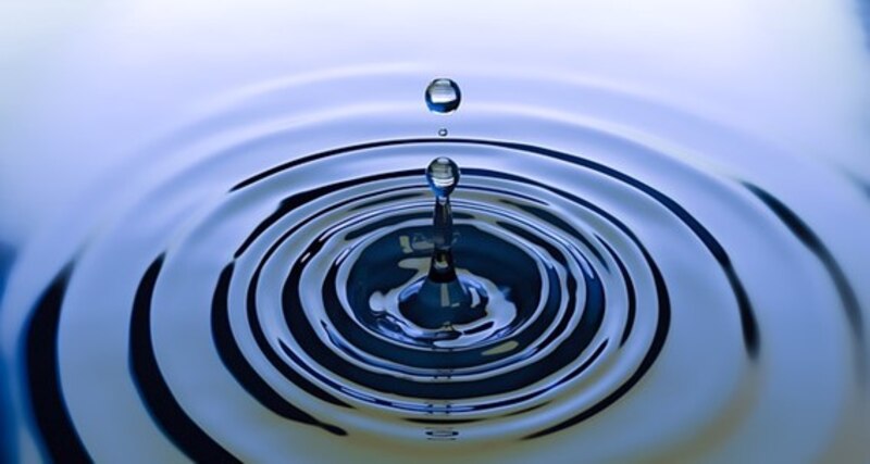 Impresionante fotografía de una gota de agua cayendo en una superficie de agua tranquila.