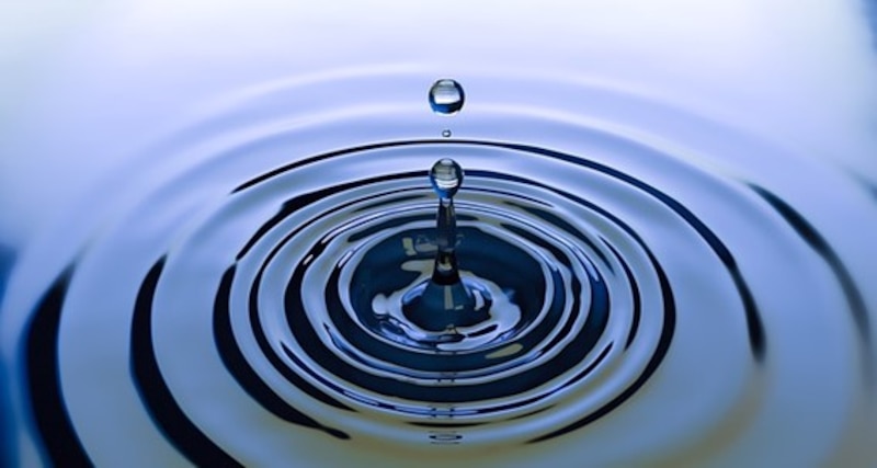 Impresionante fotografía de una gota de agua cayendo en una superficie de agua tranquila.