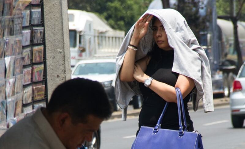 Mujer se protege del sol con una sudadera en la cabeza