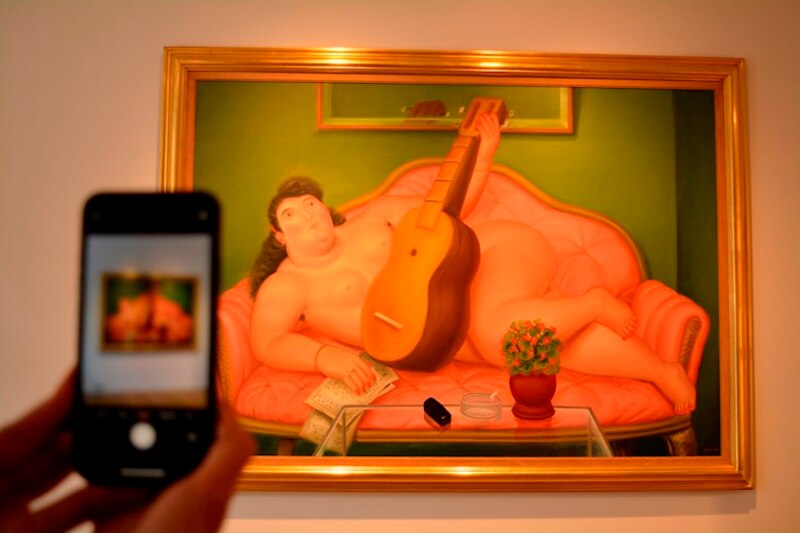 Mujer tomando una foto de una pintura de Fernando Botero