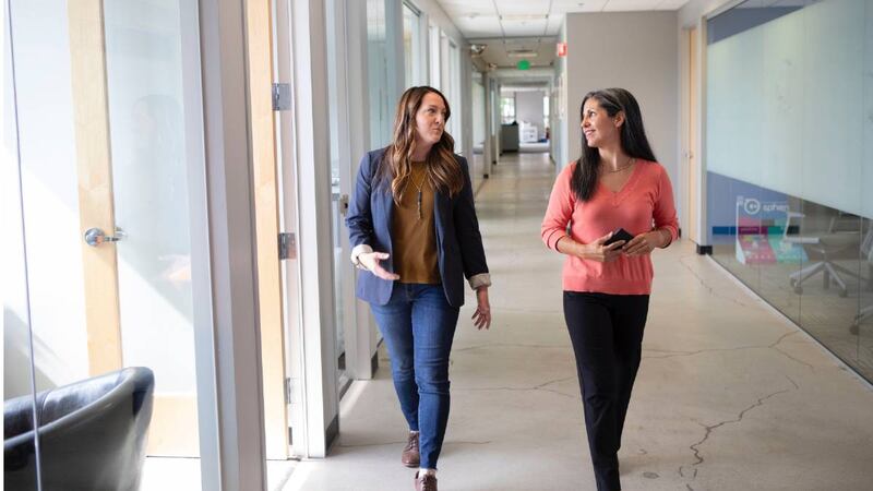 Dos mujeres caminando por un pasillo de oficina