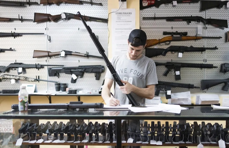 Un hombre compra una escopeta en una tienda de armas.