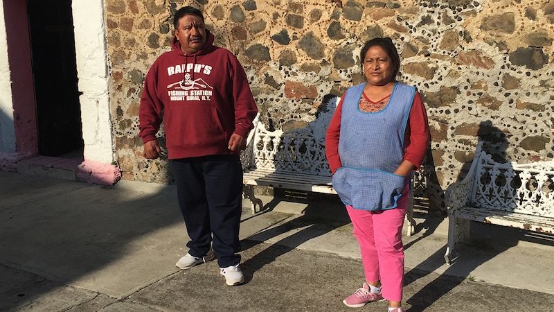 pareja de pie junto a una pared de piedra