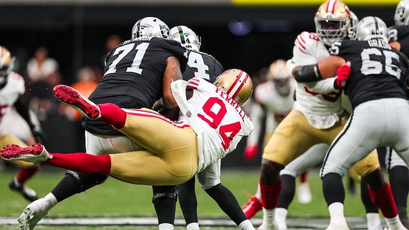 Jugador de los 49ers siendo tackleado por dos jugadores de los Raiders