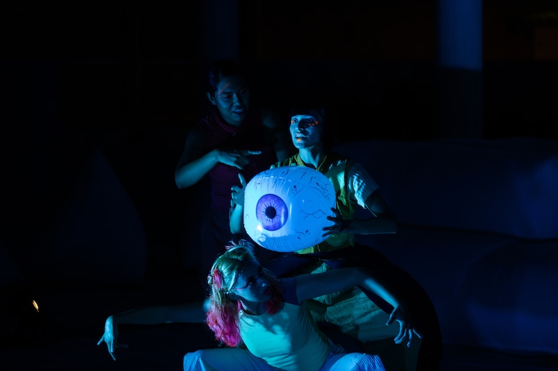 Tres mujeres jóvenes están realizando una danza ritual en la oscuridad.